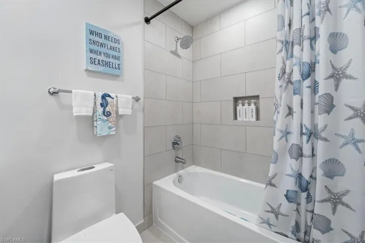 Bathroom featuring shower / bathtub combination with curtain and toilet