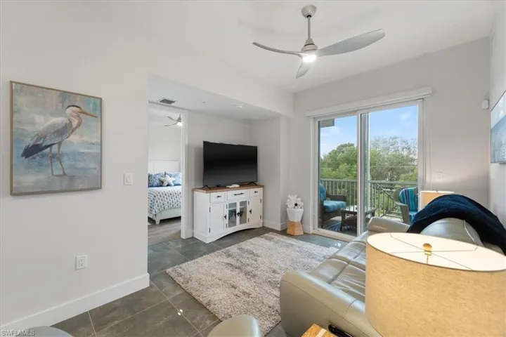 Living area with ceiling fan, dark tile patterned flooring, visible vents, and baseboards
