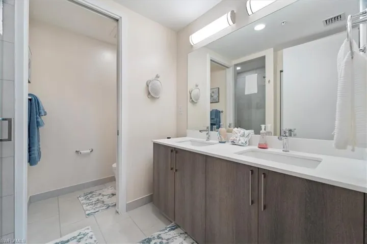 Bathroom featuring double vanity, a sink, toilet, and tile patterned floors