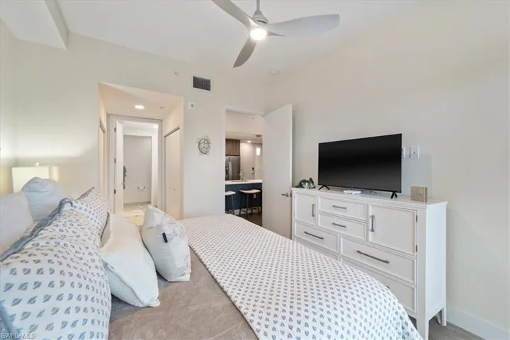 Bedroom featuring a ceiling fan, stainless steel fridge, visible vents, and baseboards