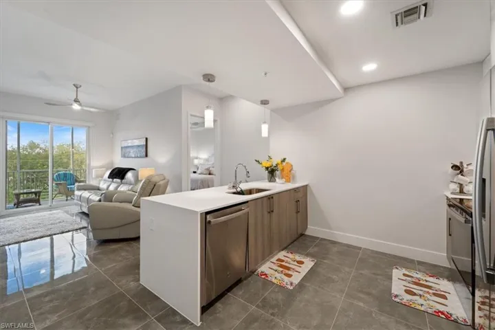 Kitchen with a peninsula, a sink, visible vents, open floor plan, and stainless steel dishwasher
