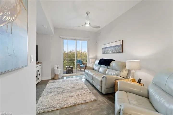 Living room with a ceiling fan, dark tile patterned flooring, and baseboards