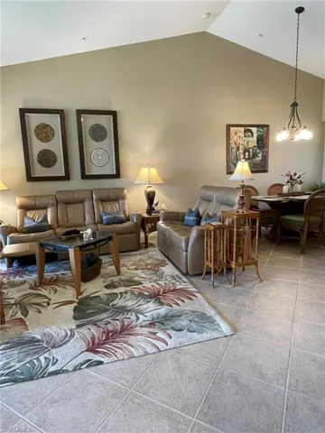 Living room with lofted ceiling, light tile patterned floors, and a chandelier