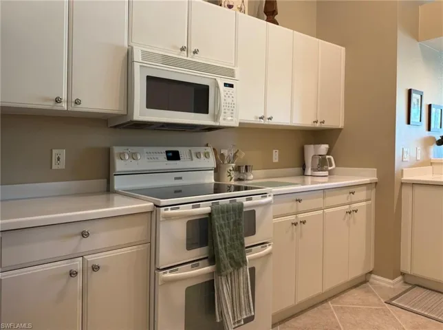 Kitchen with white appliances, light countertops, and light tile patterned floors
