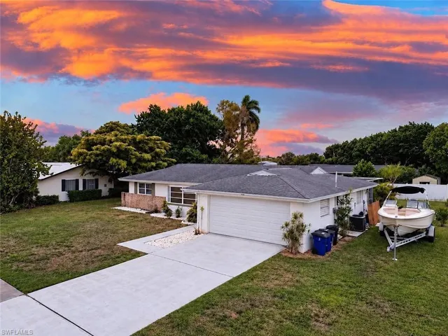 Single-story residence featuring a hipped shingle roof, white exterior finish, attached two-car garage, concrete driveway, and expansive lawn area