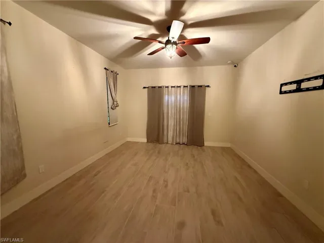 Spacious room featuring light wood-finish flooring, neutral wall tones, and white baseboards