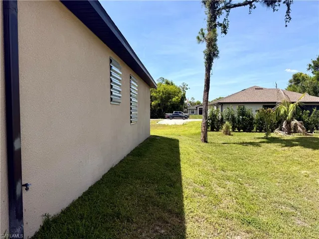 Stucco exterior with protective window coverings, dark soffits, and a matching downspout