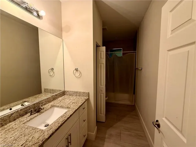 Spacious bathroom featuring a single vanity with a light-toned granite countertop and an undermount sink