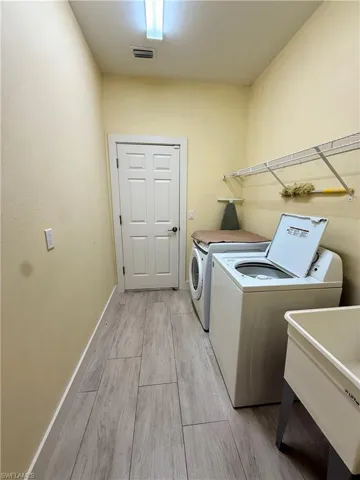 Dedicated laundry room featuring wood-finish tile flooring, a utility sink, and overhead wire shelving