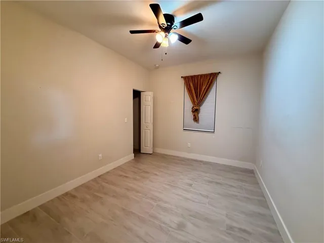 Room featuring neutral wall tones, wood-look tile flooring, and white baseboards