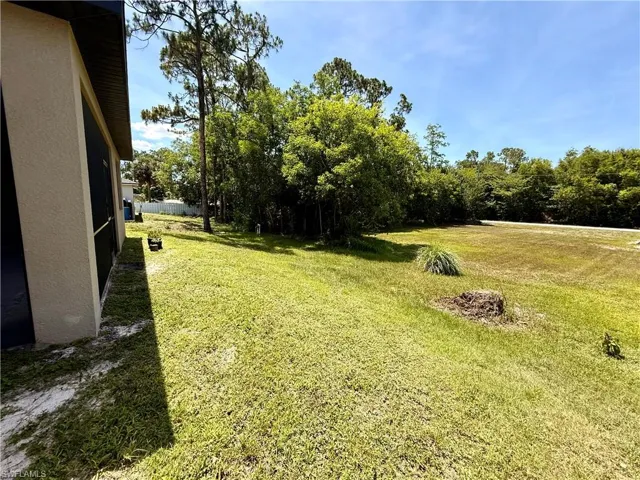 Expansive grassy yard with mature trees bordering the property