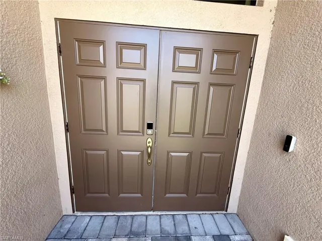 Entryway featuring double doors with raised panels and a brass-finish handle set
