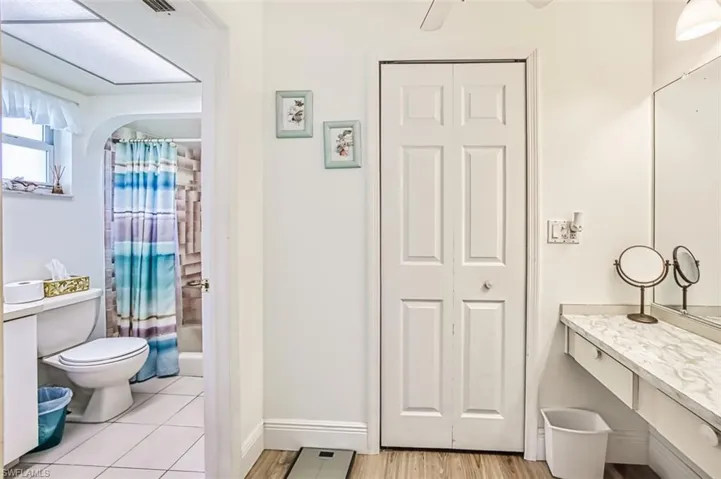 Bathroom with vanity, a closet, shower / bath combination with curtain, and light wood-style flooring