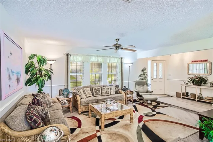 Living room with wood finished floors, a ceiling fan, and a textured ceiling