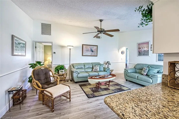 Living area with light wood-style flooring, a ceiling fan, and arched walkways