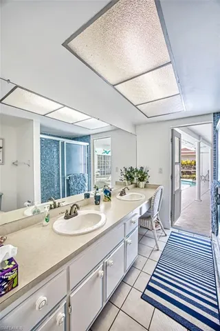 Bathroom featuring double vanity, a shower stall, and light tile patterned floors