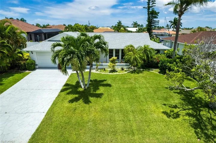 View of front of house with a garage, a front lawn, and driveway