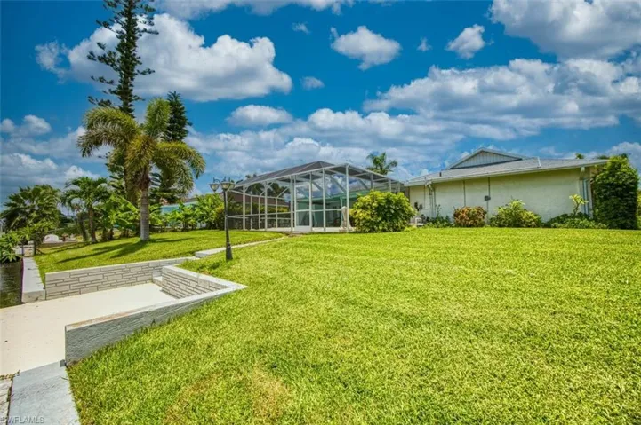 View of green lawn featuring a sunroom and glass enclosure
