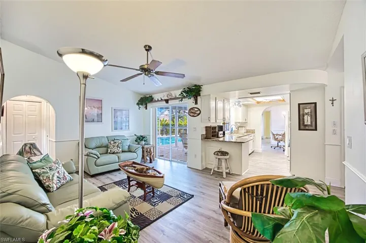 Living room featuring arched walkways, ceiling fan, light wood-type flooring, and lofted ceiling