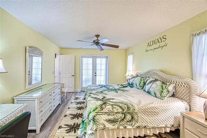 Bedroom featuring french doors, a textured ceiling, wood finished floors, multiple windows, and access to exterior