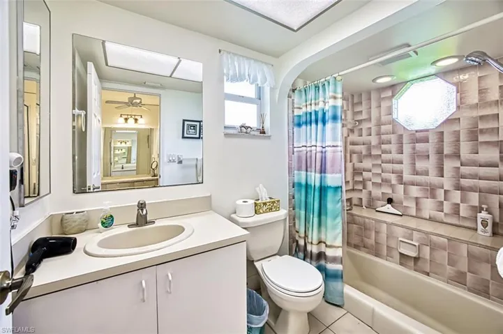 Bathroom featuring vanity, shower / bath combo with shower curtain, light tile patterned flooring, and a ceiling fan