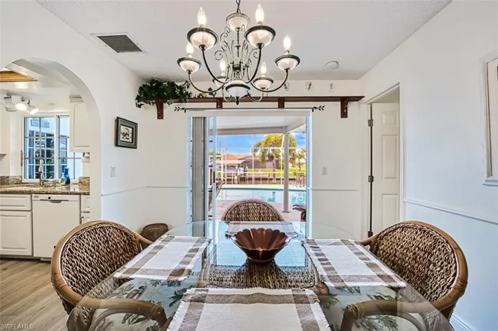 Dining room featuring hanging lights, arched walkways, light wood-style floors, and healthy amount of natural light