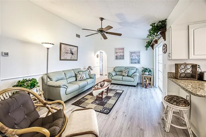 Living room featuring arched walkways, ceiling fan, and light wood-style flooring