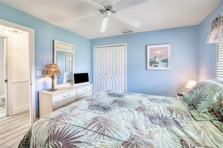 Bedroom featuring light wood finished floors, a closet, a textured ceiling, and a ceiling fan