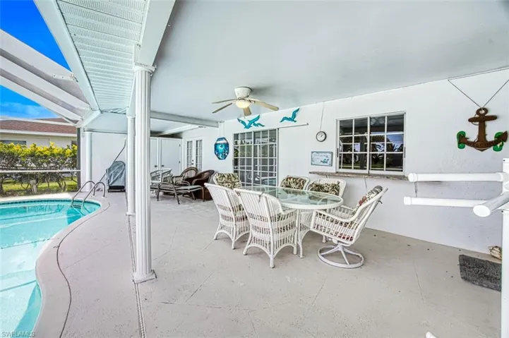 View of patio featuring ceiling fan, outdoor dining area, glass enclosure, and an outdoor pool
