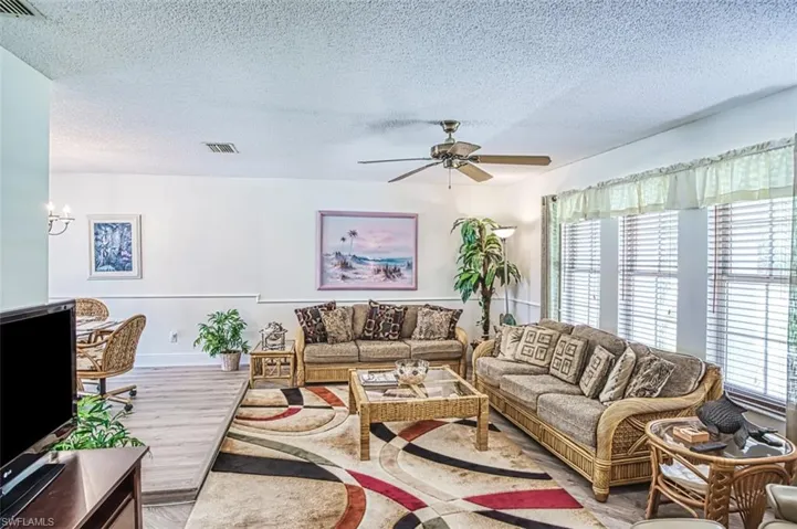 Living room featuring wood finished floors, a textured ceiling, and ceiling fan