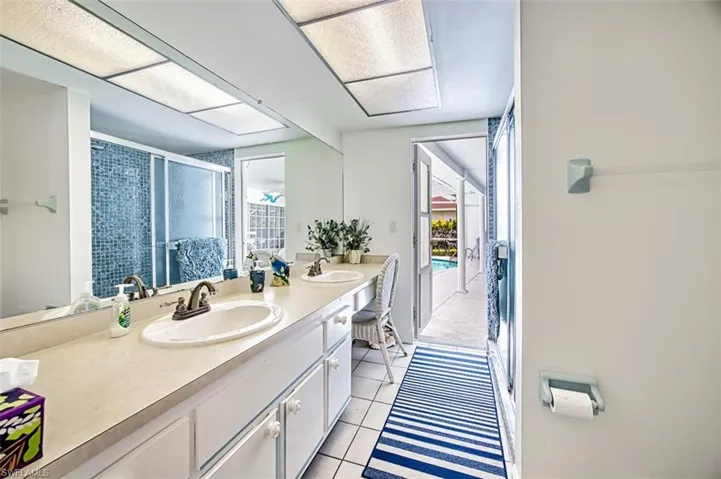 Full bath featuring double vanity, a shower stall, and light tile patterned floors