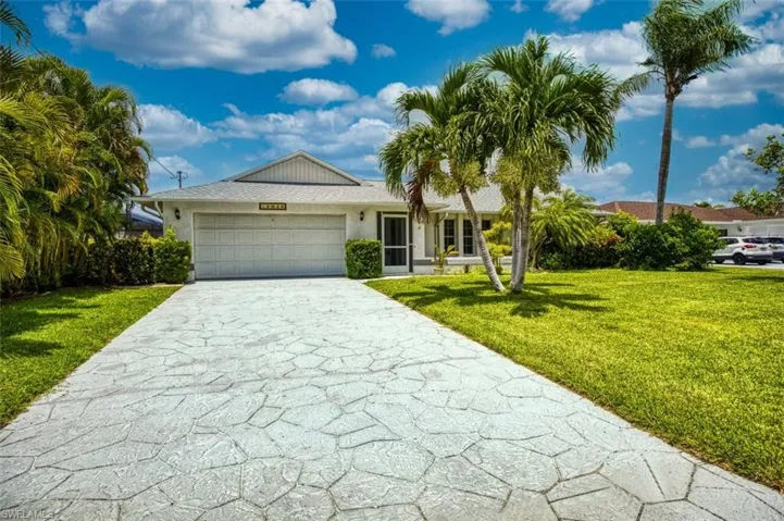 Ranch-style house with a garage, a front lawn, concrete driveway, and stucco siding