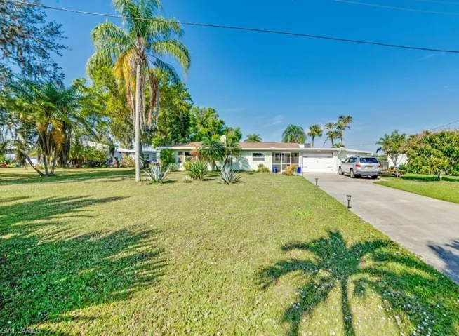 Ranch-style home featuring a garage and a front lawn