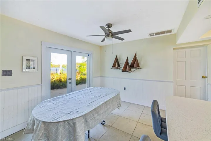 Dining room featuring light tile patterned flooring, ceiling fan, and french doors