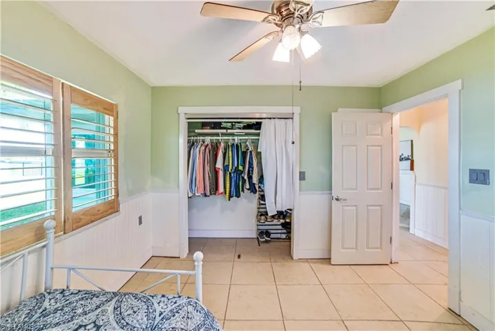 Bedroom with light tile patterned floors, ceiling fan, and a closet