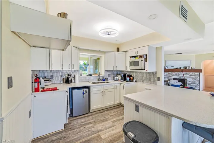 Kitchen with sink, a breakfast bar area, dishwashing machine, kitchen peninsula, and white cabinets