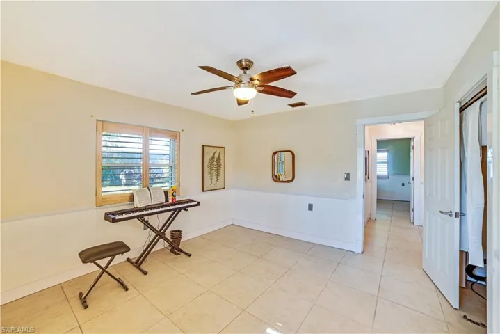 Empty room with ceiling fan, plenty of natural light, and light tile patterned floors