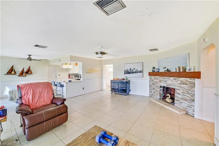 Tiled living room with ceiling fan and a stone fireplace