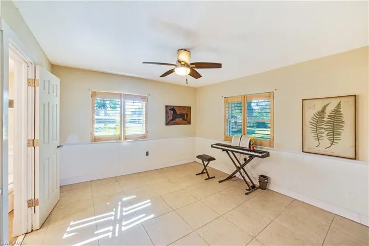 Tiled spare room featuring ceiling fan
