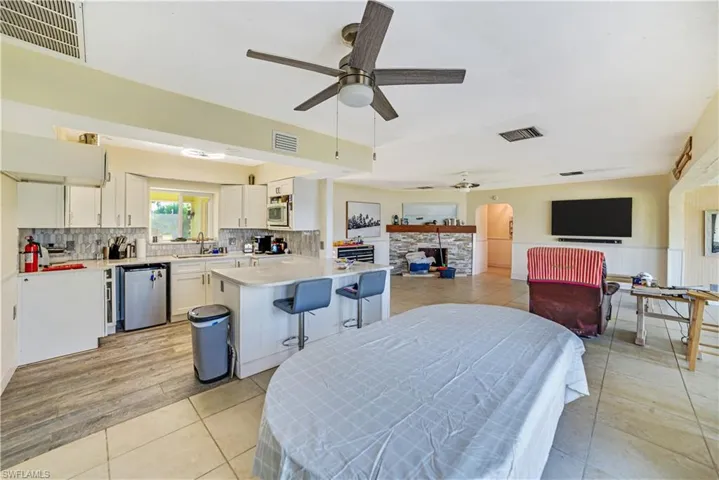Dining room with light tile patterned flooring, ceiling fan, a fireplace, and sink