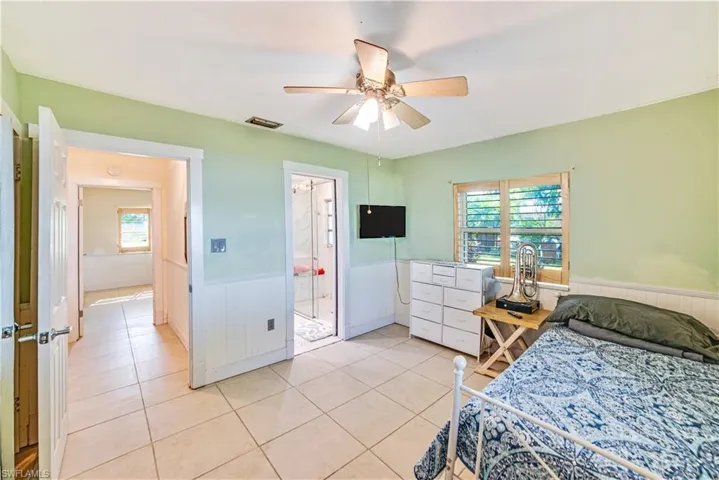 Bedroom featuring ceiling fan, multiple windows, and light tile patterned floors