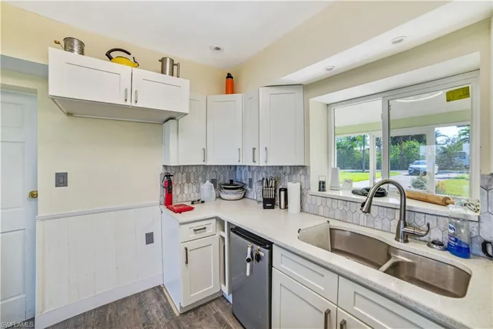 Kitchen featuring sink, stainless steel dishwasher, white cabinets, and dark wood-type flooring