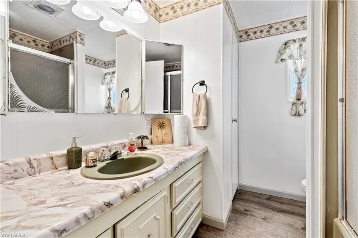 Bathroom featuring a shower stall, vanity, and light wood-type flooring