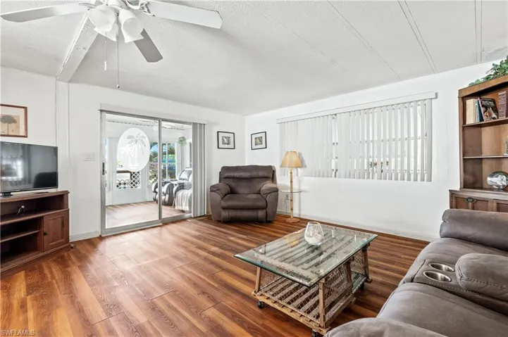 Living room with wood finished floors, a textured ceiling, and a ceiling fan