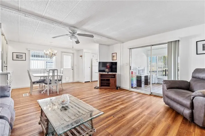 Living room featuring light wood-style floors, ceiling fan, and hanging lights
