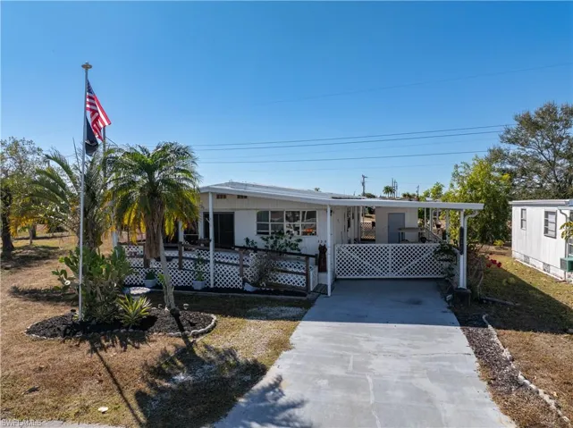 Manufactured / mobile home with concrete driveway, a deck, and a carport