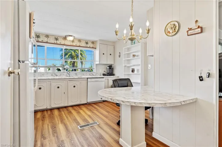 Kitchen with light countertops, open shelves, white cabinets, white appliances, and a breakfast bar
