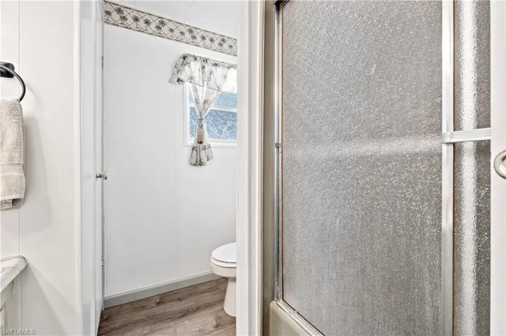 Full bath featuring light wood finished floors and toilet