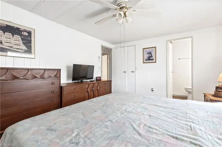 Bedroom with a ceiling fan, wooden walls, and ensuite bath