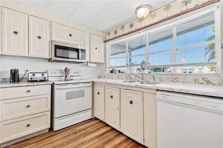 Kitchen with white appliances, light countertops, light wood finished floors, and white cabinets